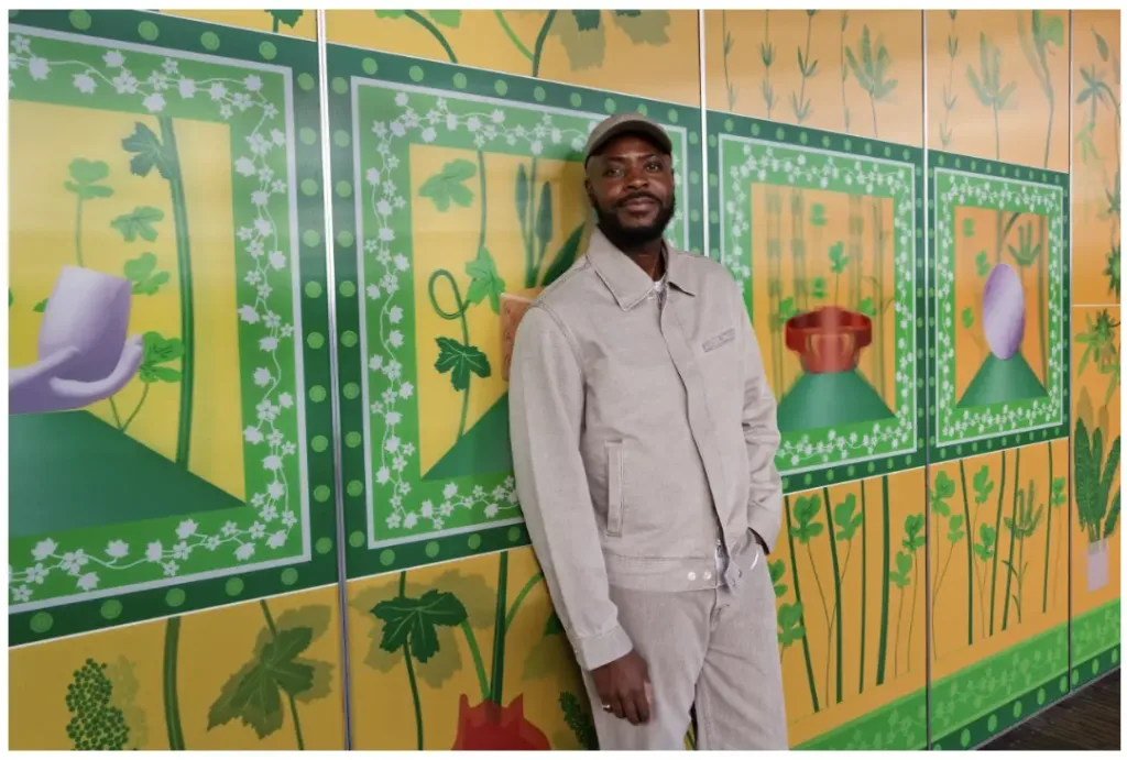 A man is positioned in front of a lively, multicolored wall, displaying an assortment of bright and engaging colors.